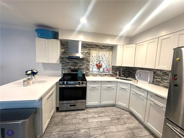 kitchen featuring white cabinets, stainless steel appliances, wall chimney exhaust hood, and kitchen peninsula