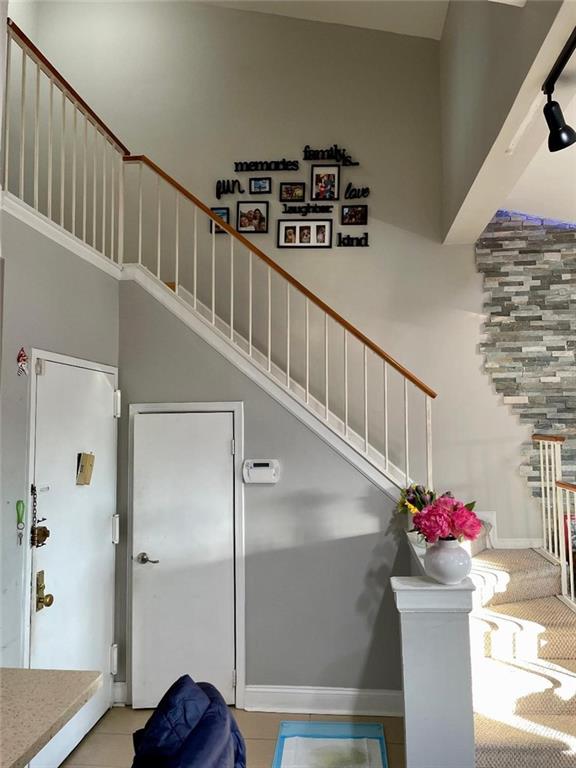 stairway with tile patterned floors and a high ceiling