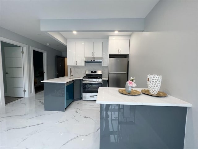 kitchen featuring blue cabinetry, a breakfast bar, stainless steel appliances, kitchen peninsula, and white cabinetry