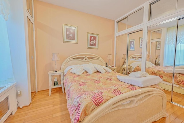 bedroom with multiple closets and light hardwood / wood-style floors