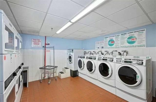 washroom featuring stacked washer and clothes dryer, tile walls, and independent washer and dryer