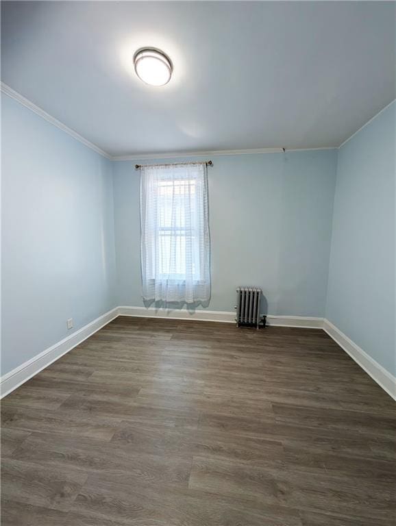 spare room featuring crown molding, radiator heating unit, and dark hardwood / wood-style flooring