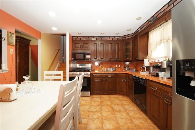 kitchen featuring dark brown cabinets, backsplash, and black appliances