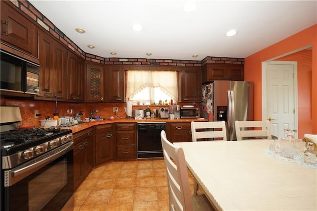 kitchen featuring dark brown cabinets, black appliances, sink, and tasteful backsplash