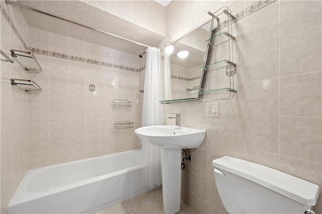 bathroom with tile walls, shower / bathtub combination with curtain, tile patterned floors, and toilet