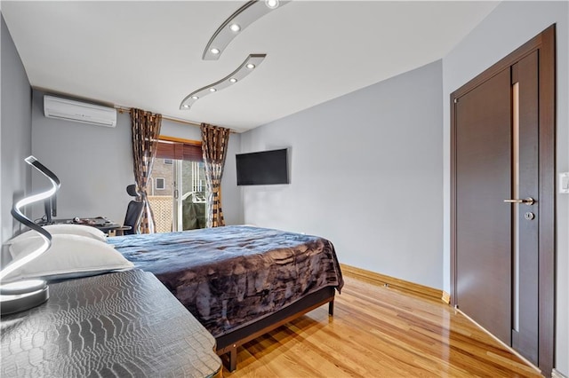 bedroom with light hardwood / wood-style floors and an AC wall unit