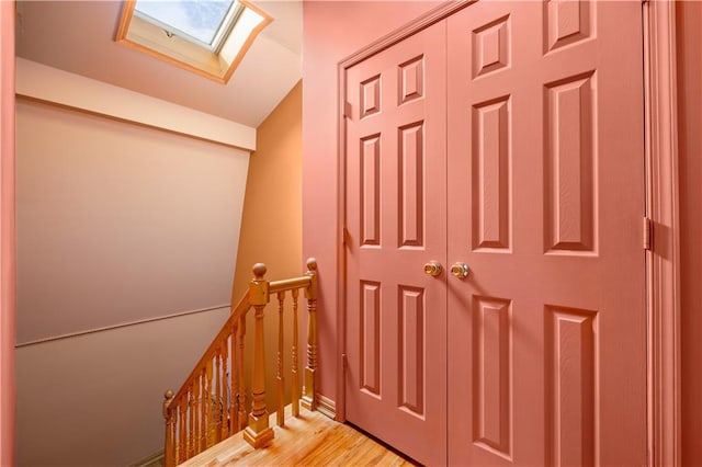 staircase featuring lofted ceiling with skylight and hardwood / wood-style floors