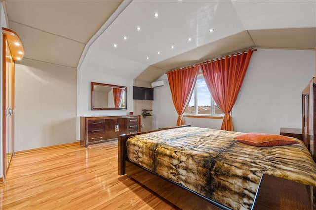 bedroom featuring lofted ceiling, an AC wall unit, and light wood-type flooring