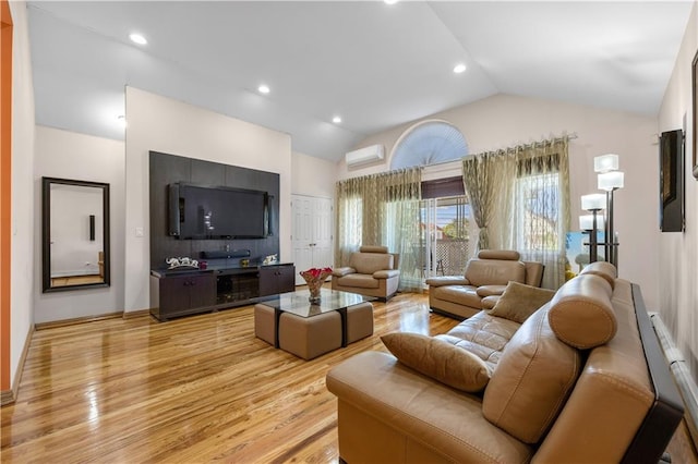 living room with lofted ceiling, a wall mounted air conditioner, and light hardwood / wood-style flooring