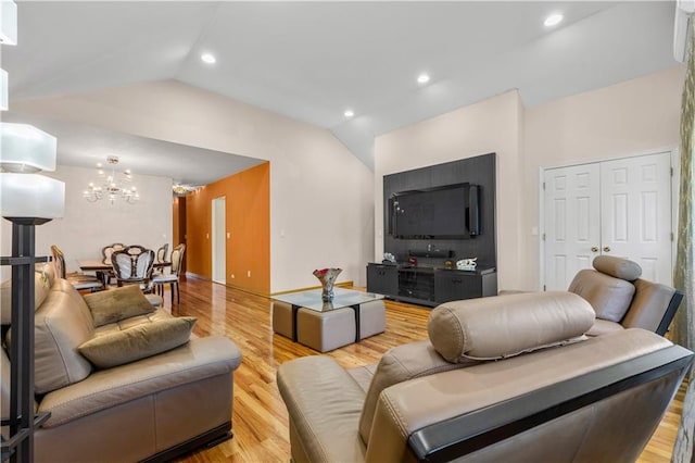 living room with lofted ceiling, a chandelier, and light hardwood / wood-style floors