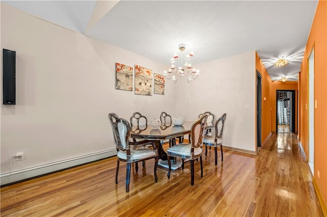 dining space with light hardwood / wood-style flooring, a chandelier, and a baseboard heating unit