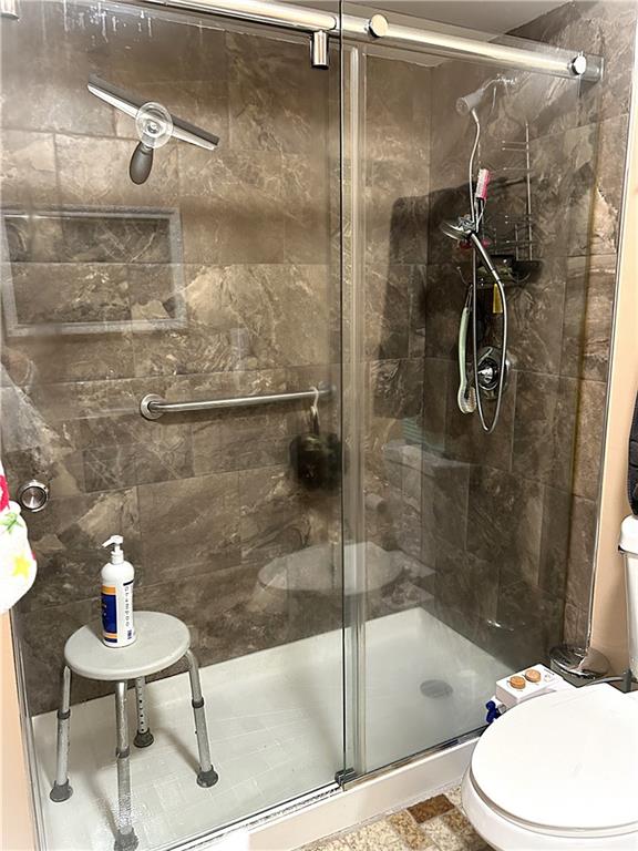 bathroom with a shower with door and toilet