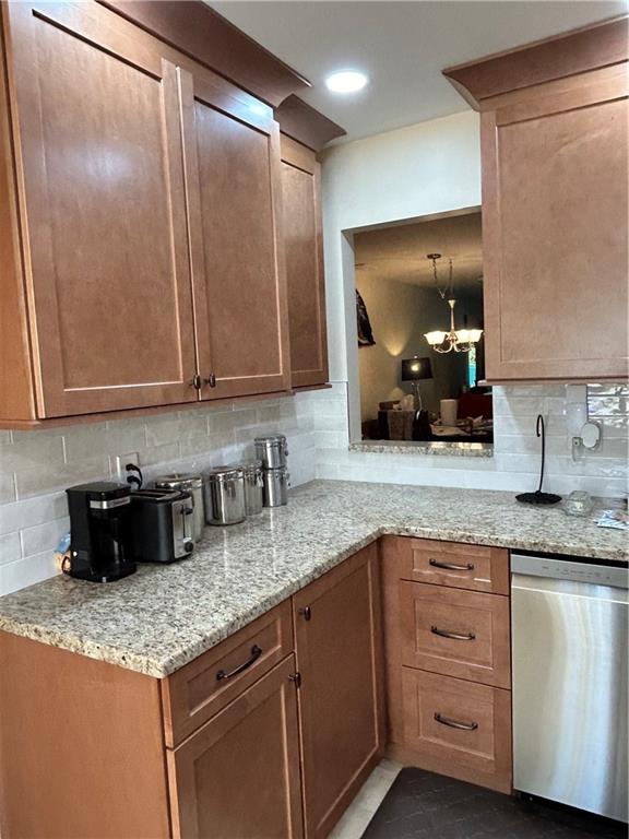 119 Stonegate Dr Unit 119, Staten Island, NY 10304 - kitchen featuring a chandelier, tasteful backsplash, light stone countertops, and stainless steel dishwasher