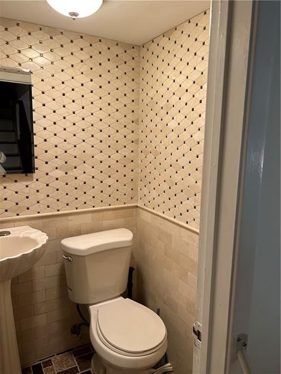 bathroom with toilet and tile walls