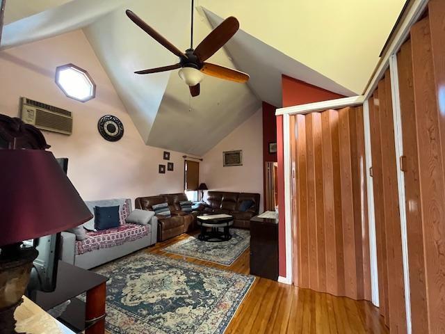 living room featuring ceiling fan, a wall mounted AC, wood finished floors, and lofted ceiling