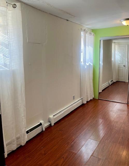 spare room featuring a baseboard radiator and wood finished floors