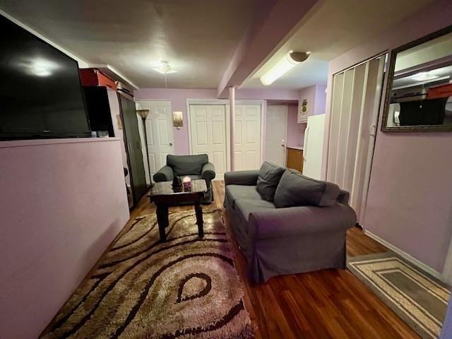 living room featuring dark wood-type flooring and beamed ceiling