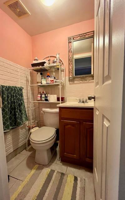 bathroom featuring vanity, visible vents, toilet, wainscoting, and tile patterned floors