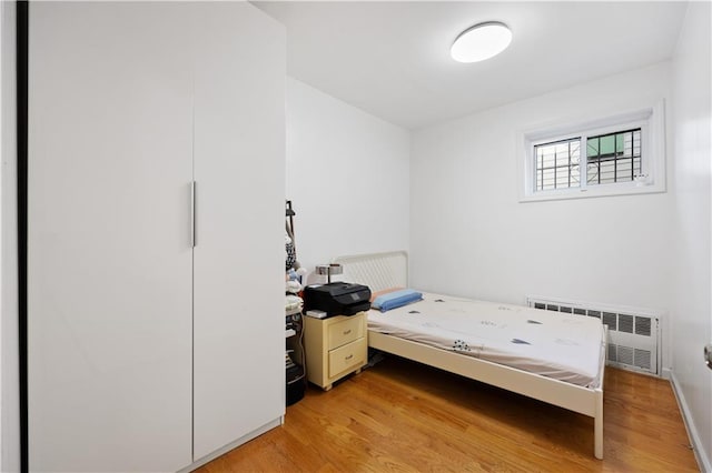 bedroom with radiator and light hardwood / wood-style floors