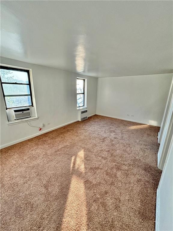 carpeted empty room featuring cooling unit and radiator heating unit