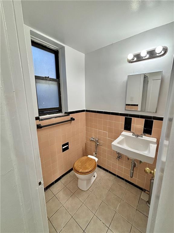 bathroom with tile patterned flooring, sink, tile walls, and toilet