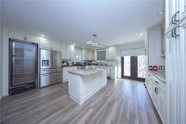 kitchen with white cabinets, a center island, stainless steel appliances, and hanging light fixtures