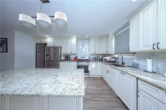 kitchen with appliances with stainless steel finishes, backsplash, light stone counters, sink, and hanging light fixtures