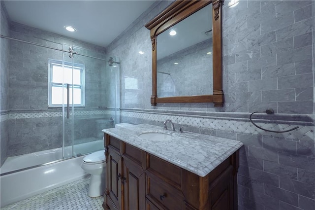 full bathroom featuring toilet, vanity, tile walls, and combined bath / shower with glass door