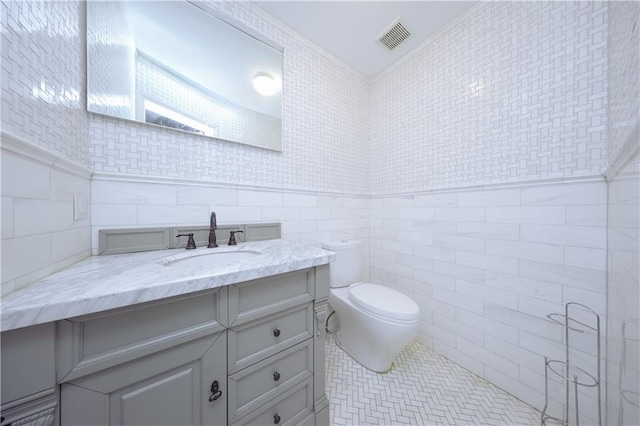 bathroom featuring tile patterned flooring, vanity, tile walls, and toilet