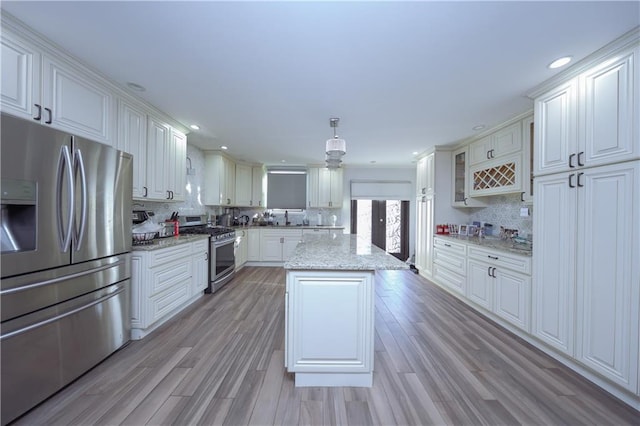 kitchen with light stone countertops, backsplash, stainless steel appliances, pendant lighting, and a center island