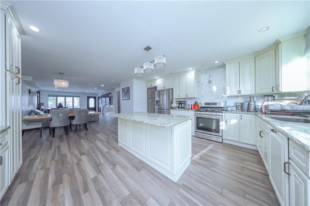 kitchen featuring stainless steel appliances, a notable chandelier, backsplash, decorative light fixtures, and a kitchen island