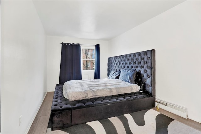 bedroom with a baseboard radiator and wood-type flooring