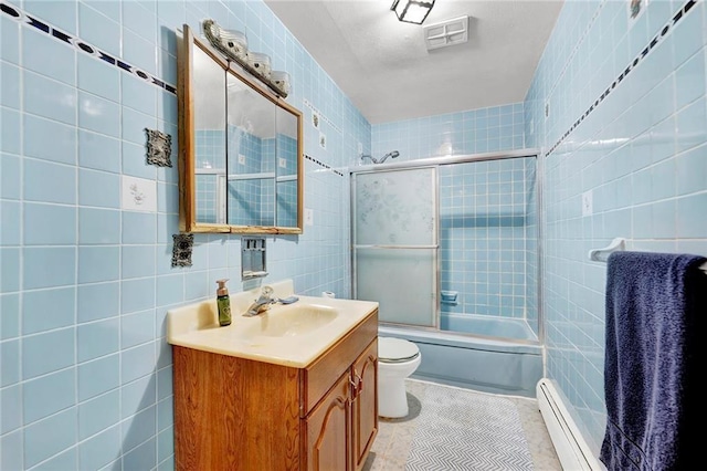 full bathroom with tile patterned floors, toilet, vanity, bath / shower combo with glass door, and tile walls