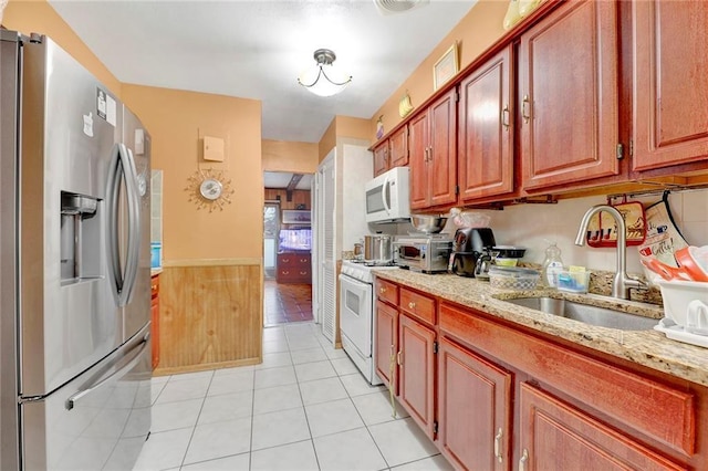 kitchen with white appliances, light tile patterned flooring, light stone countertops, and sink