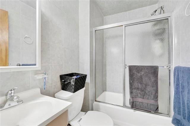 full bathroom featuring vanity, toilet, tile walls, and enclosed tub / shower combo