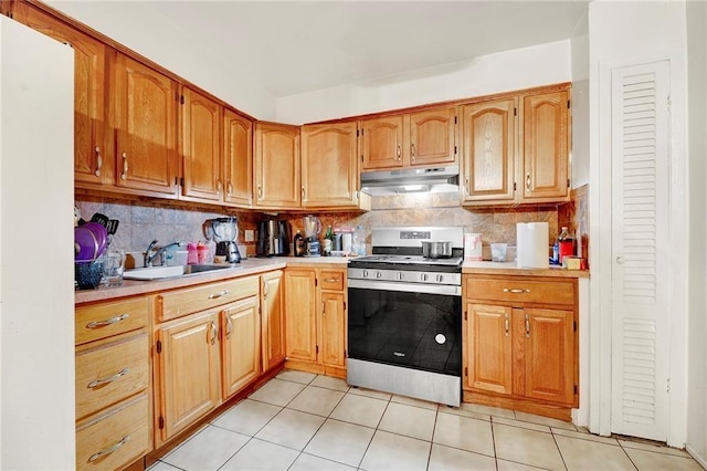 kitchen featuring backsplash, sink, stainless steel range, and light tile patterned floors