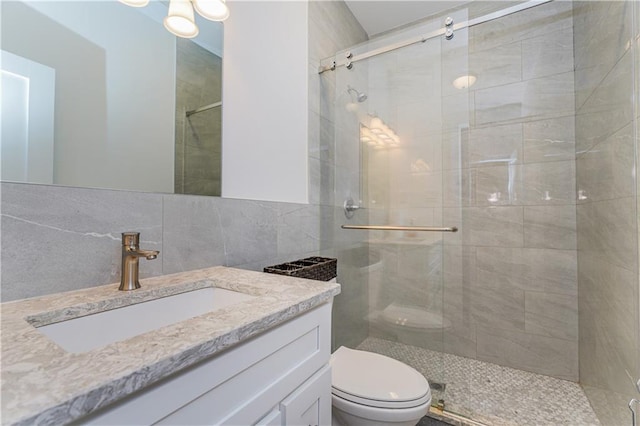 bathroom featuring a shower with door, vanity, backsplash, and toilet