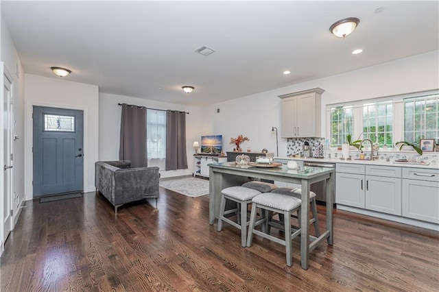 kitchen with dark wood-type flooring, tasteful backsplash, a center island, stainless steel dishwasher, and gray cabinets