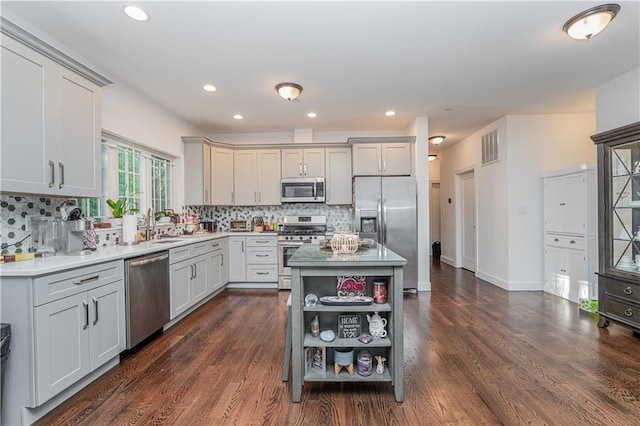 kitchen with stainless steel appliances, a center island, dark wood-type flooring, and backsplash