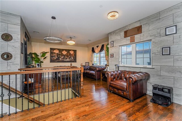 living room with hardwood / wood-style floors, tile walls, and a notable chandelier