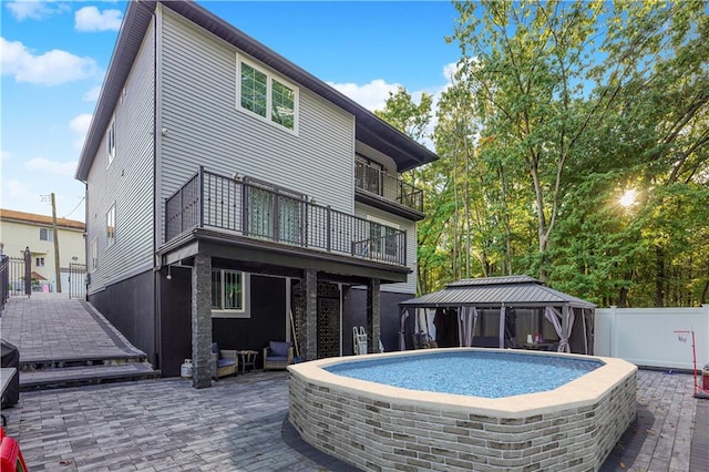 rear view of property featuring a gazebo, a balcony, and a patio area