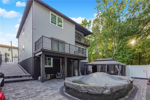 rear view of property featuring a gazebo, a balcony, a covered pool, and a patio area