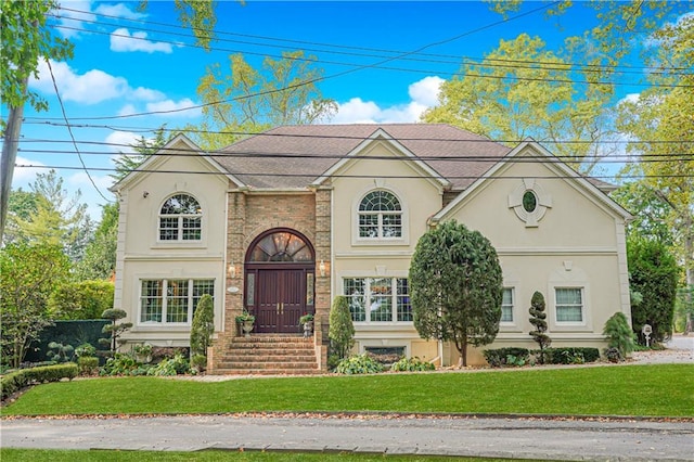 view of front of house featuring stucco siding and a front lawn