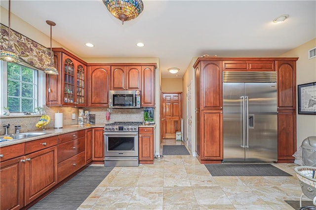 kitchen with visible vents, glass insert cabinets, tasteful backsplash, hanging light fixtures, and stainless steel appliances