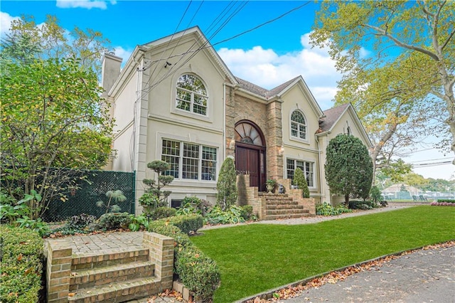 view of front of home featuring a front lawn, stucco siding, and a chimney