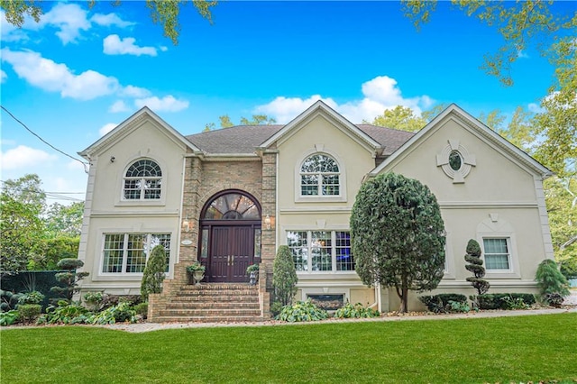 view of front of home featuring brick siding, a front yard, and stucco siding
