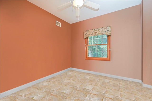 spare room with baseboards, ceiling fan, and visible vents