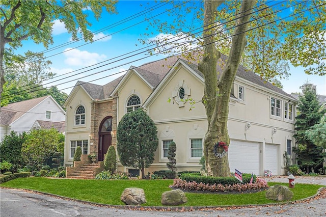 traditional home featuring an attached garage, driveway, a front yard, and stucco siding