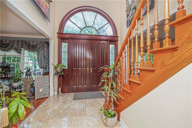 entrance foyer with stairs, marble finish floor, and a towering ceiling