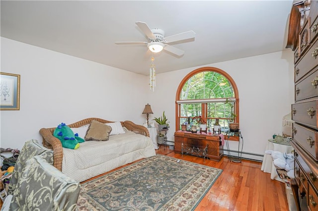 bedroom featuring ceiling fan, a baseboard heating unit, wood finished floors, and a baseboard radiator